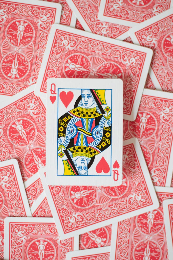 about-us-02 Close-up of Queen of Hearts surrounded by scattered red back playing cards.